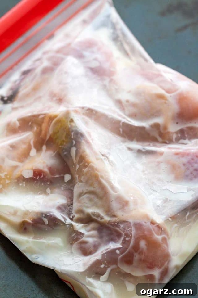 Golden Crispy Air Fryer Chicken 4 Raw chicken drumstick marinating in buttermilk inside a sealed zipper bag