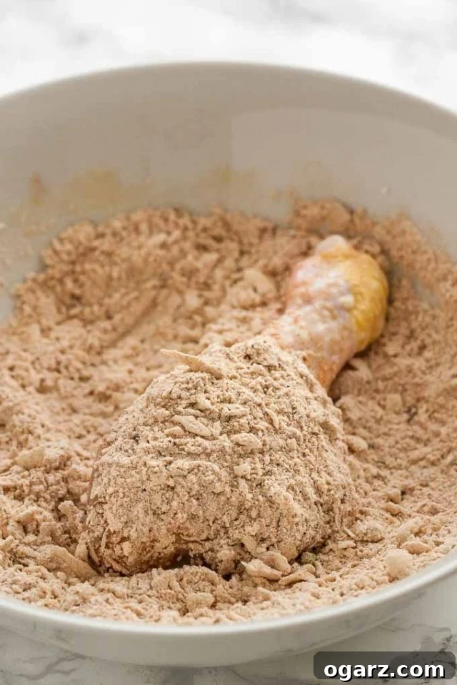 Golden Crispy Air Fryer Chicken 5 Uncooked chicken drumstick coated in a seasoned breading mixture in a shallow bowl