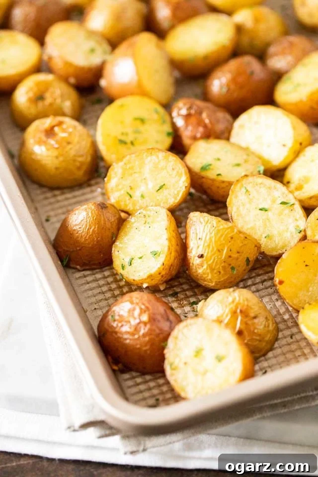 Ultimate Roasted Potatoes 2 A baking sheet with roasted potatoes, garnished with parsley, ready to be served.