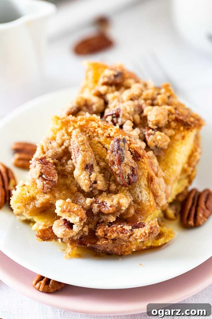 A close-up of a single piece of Overnight French Toast Casserole, beautifully presented on a white plate and garnished with extra pecans, ready to be enjoyed.