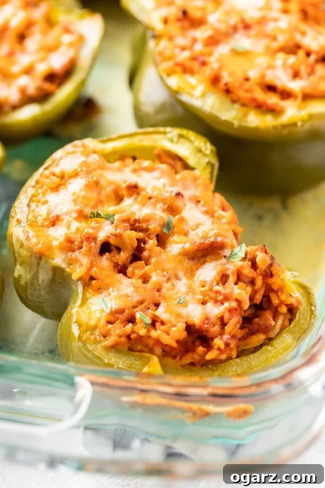 Classic Stuffed Green Peppers 3 Close-up of glass baking dish with baked stuffed green peppers garnished with parsley.