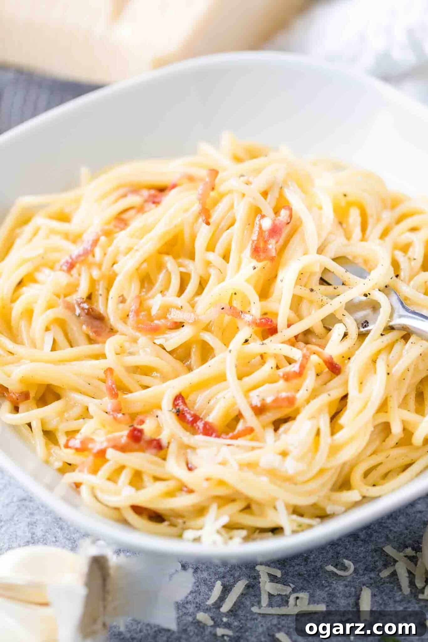Authentic Roman Carbonara 2 Spaghetti Carbonara on a white plate with a fork in it.