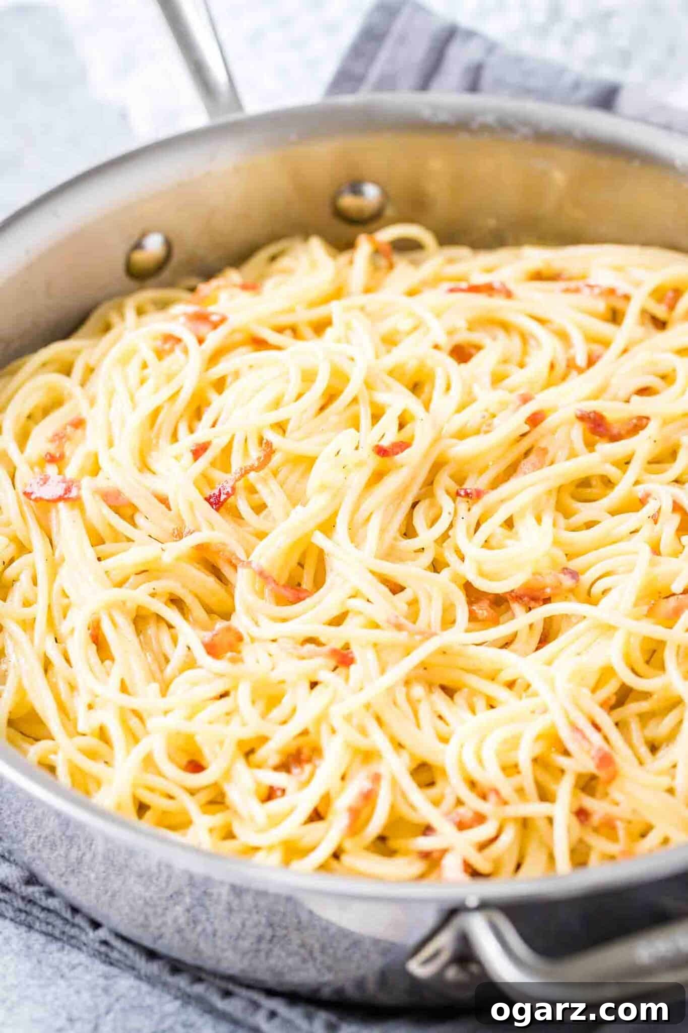 Pasta Carbonara is an easy Italian recipe that can be made in less than 20 minutes from start to finish and is so creamy and delicious. This classic carbonara sauce can be served with your favorite kind of pasta like spaghetti or fettuccine and makes an indulgent and quick weeknight dinner! #pastacarbonara #pastarecipes #spaghetti A stainless steel pan with spaghetti carbonara