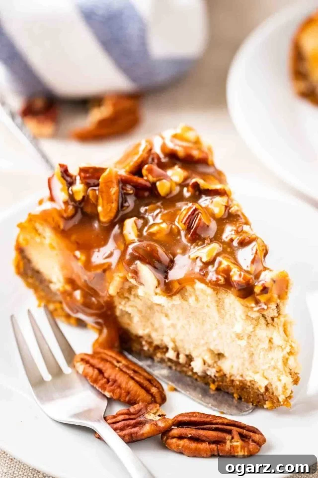 A slice of cheesecake topped with pecan nuts and caramel sauce on a small white plate with a fork.