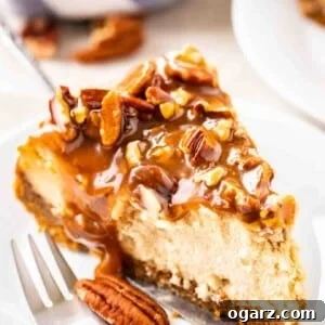 A slice of cheesecake topped with pecan nuts and caramel sauce on a small white plate with a fork.