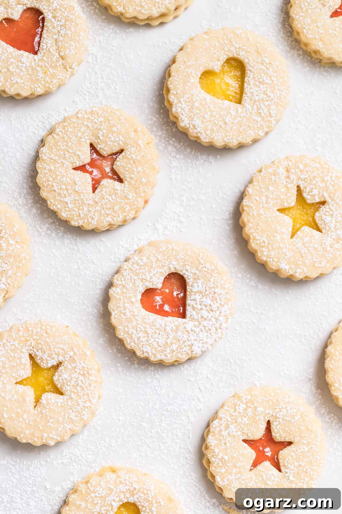 Beautifully crafted Linzer cookies arranged on parchment paper, showcasing their delicate dusting of powdered sugar and vibrant jam centers.