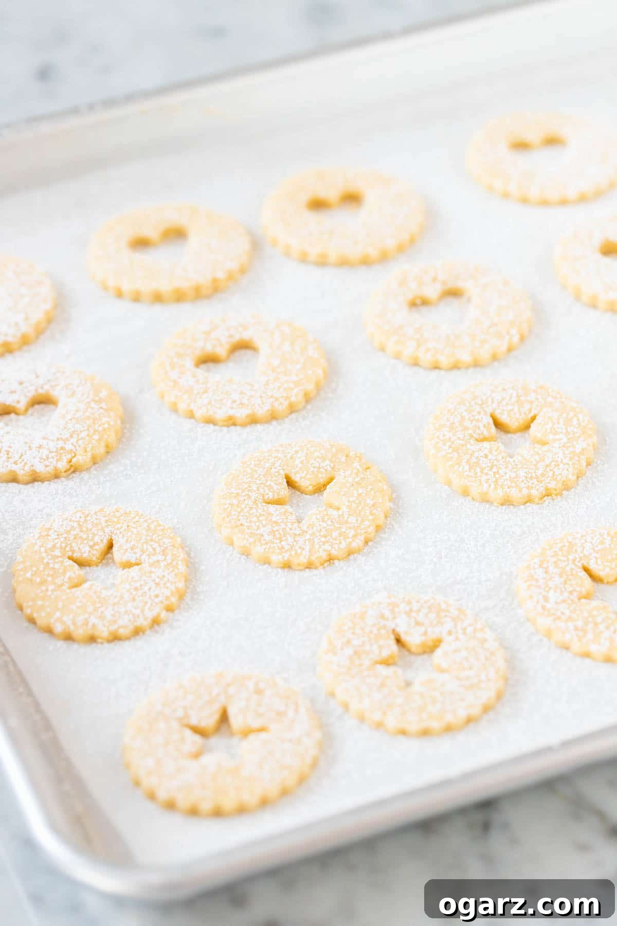 Assembled Linzer Cookies, artfully dusted with powdered sugar and revealing their vibrant jam filling, arranged symmetrically for a perfect finish.