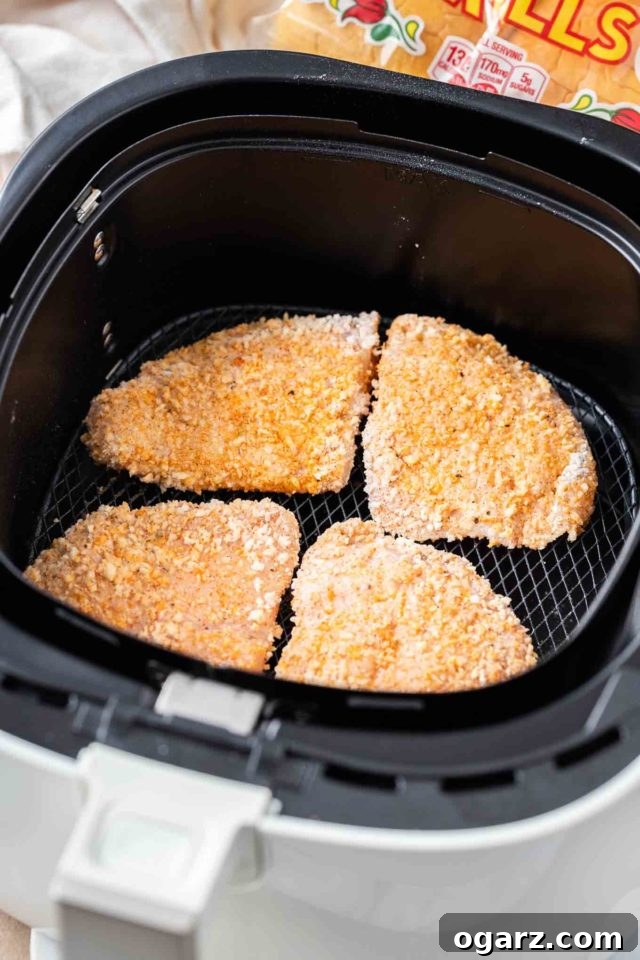 Crispy Air Fried Chicken Sandwiches 3 Four breaded chicken breasts in an air fryer basket.