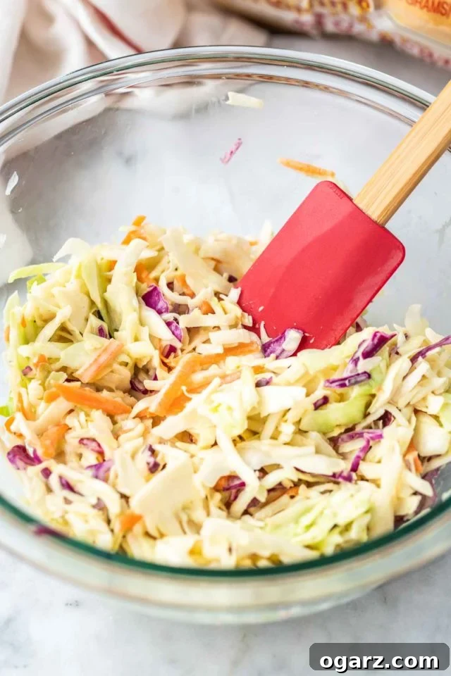 Crispy Air Fried Chicken Sandwiches 5 A glass bowl of coleslaw with a red spatula with a wooden handle in it.