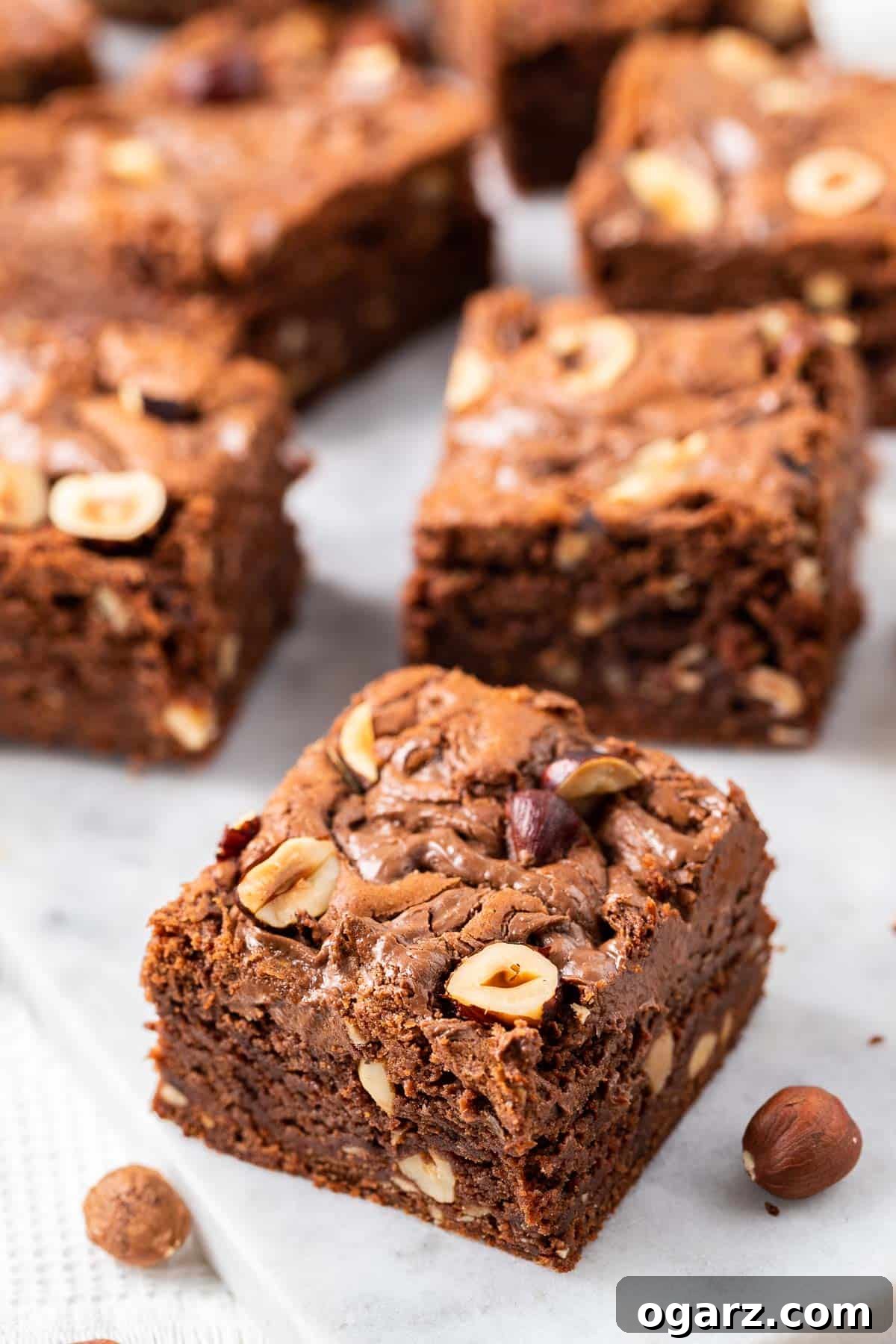 Perfectly cut Nutella brownies resting on parchment paper, showcasing their fudgy texture and delicious hazelnut toppings.