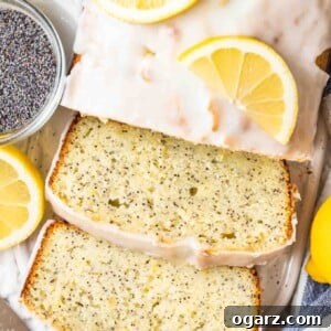 top-down view of lemon poppy seed cake with two slices cut off on a white ceramic cutting board, garnished with lemons next to a glass bowl with poppy seeds