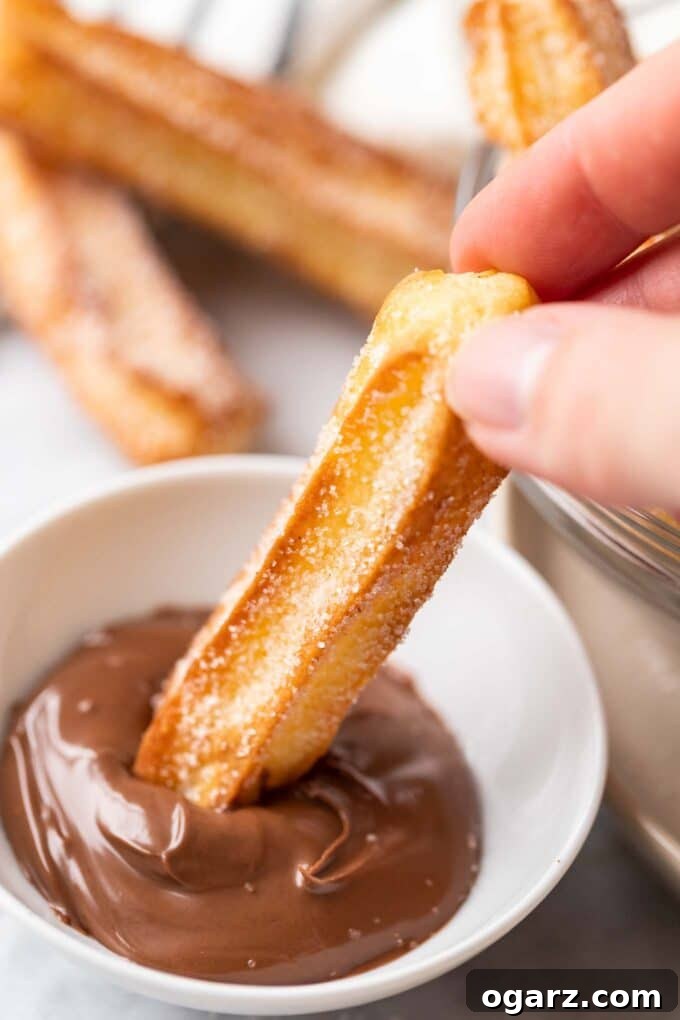 Air-Fried Churro Perfection 5 sugared churro being dipped into nutella, churros in the background