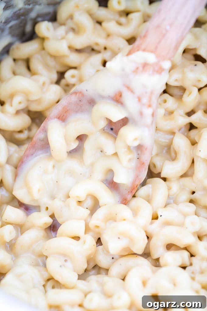 Creamy Mac and Cheese in a serving dish with a wooden cooking spoon resting in it