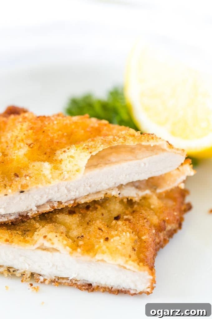 Schnitzel, cut in half, stacked on a plate, garnished with lemon and parsley