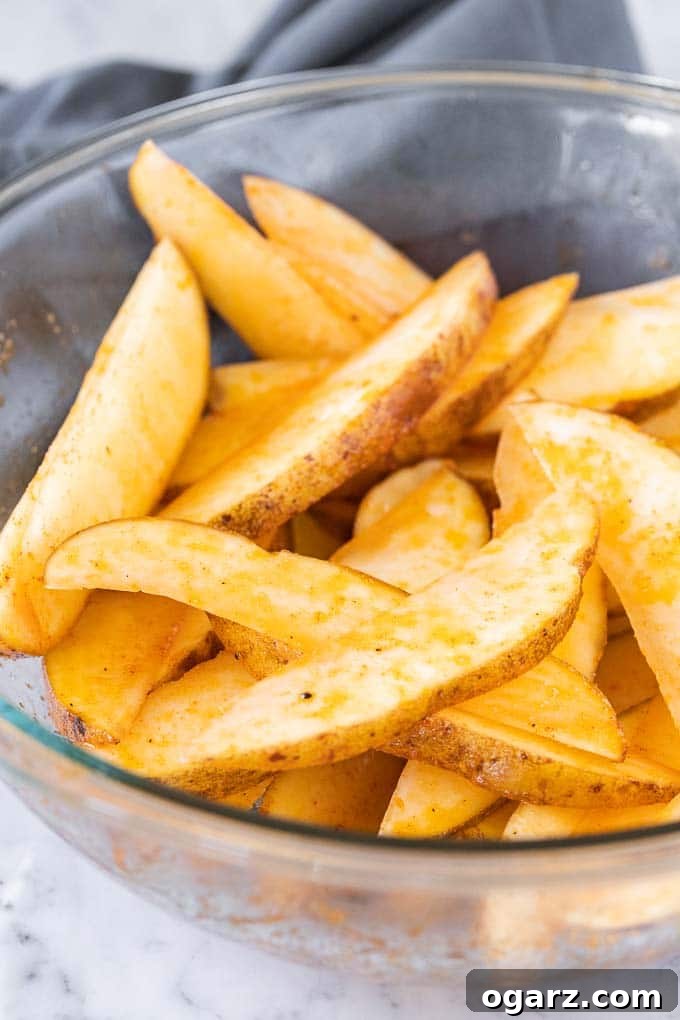 Crispy Air Fryer Potato Wedges 3 Cut Russet Potato Wedges in a glass bowl, ready for seasoning.