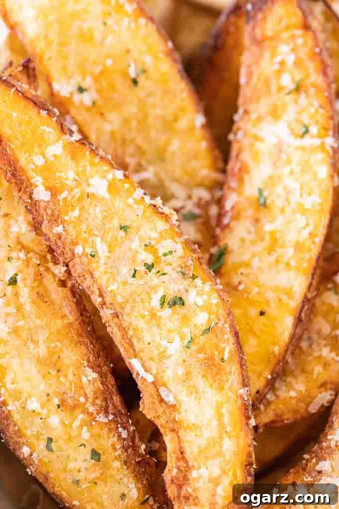 Crispy Air Fryer Potato Wedges 4 Close-up of Air Fryer Potato Wedges, garnished with Parmigiano cheese and fresh parsley in a white bowl.