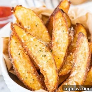 Air Fryer Potato Wedges in a white bowl, garnished with Parmesan cheese and parsley.