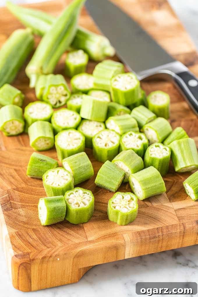 Crispy Air Fryer Okra 3 Freshly cut raw Okra on a wooden cutting board with a kitchen knife, showing preparation for air frying.