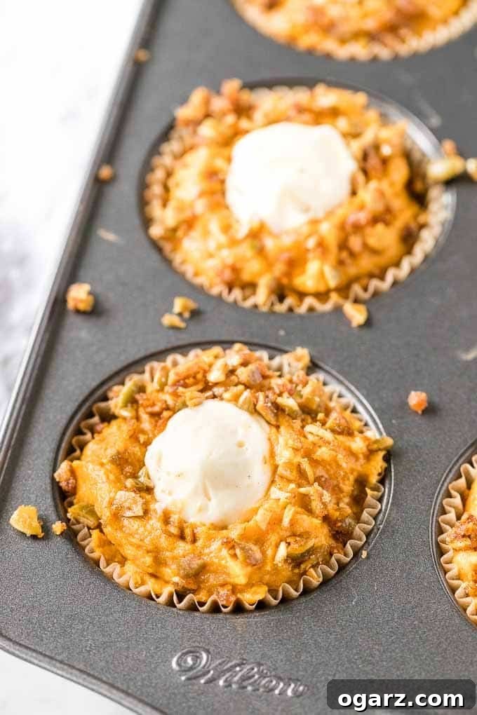 A muffin pan brimming with pumpkin muffin batter, ready for baking, showcasing the generous filling and topping.