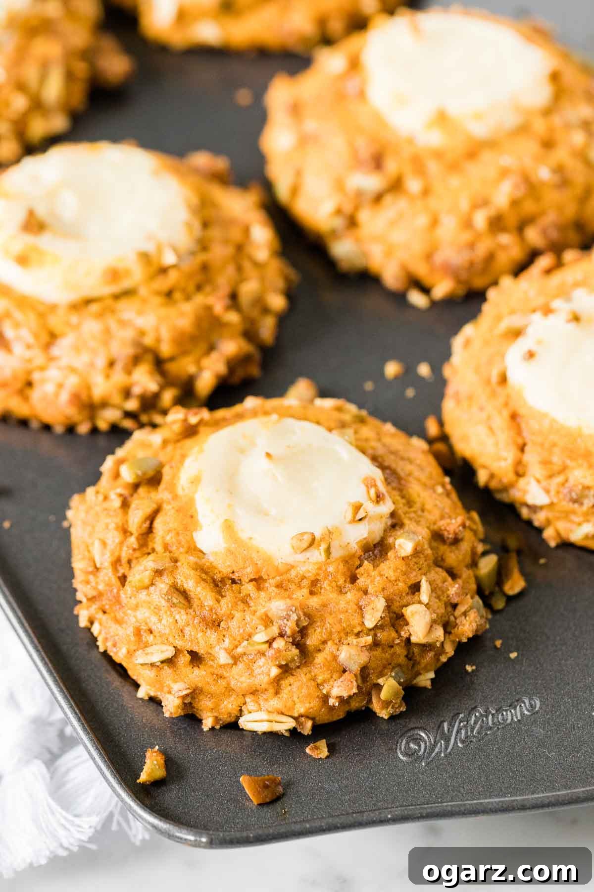 A batch of perfectly baked pumpkin cream cheese muffins still nestled in their muffin pan, showcasing their golden tops and tempting appearance.