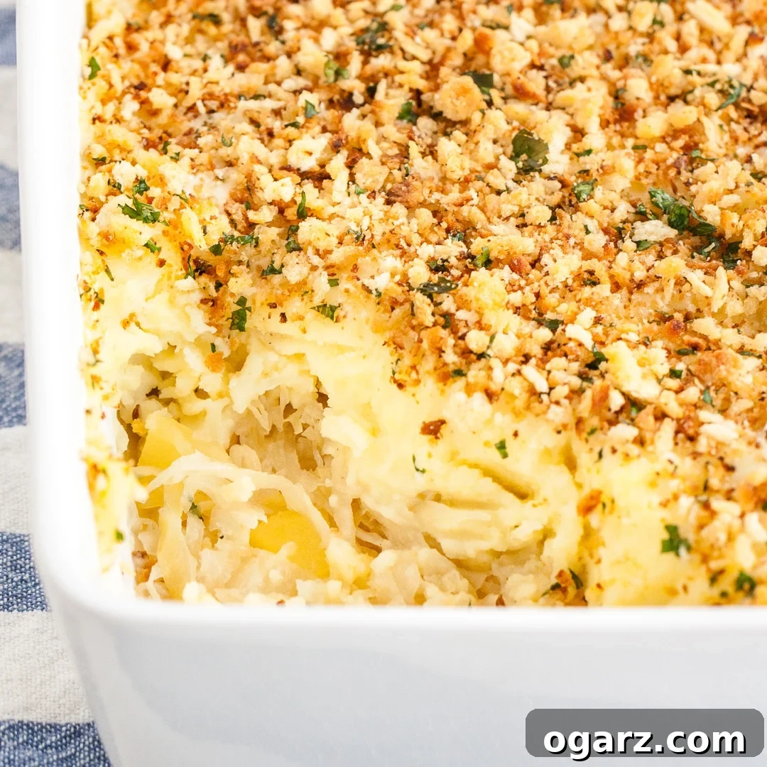 Tangy Kraut and Creamy Potato Bake 8 A final close-up of the Sauerkraut Mashed Potato Casserole in a white baking dish, with a portion removed, highlighting the delicious layers, set on a blue and white dishtowel.