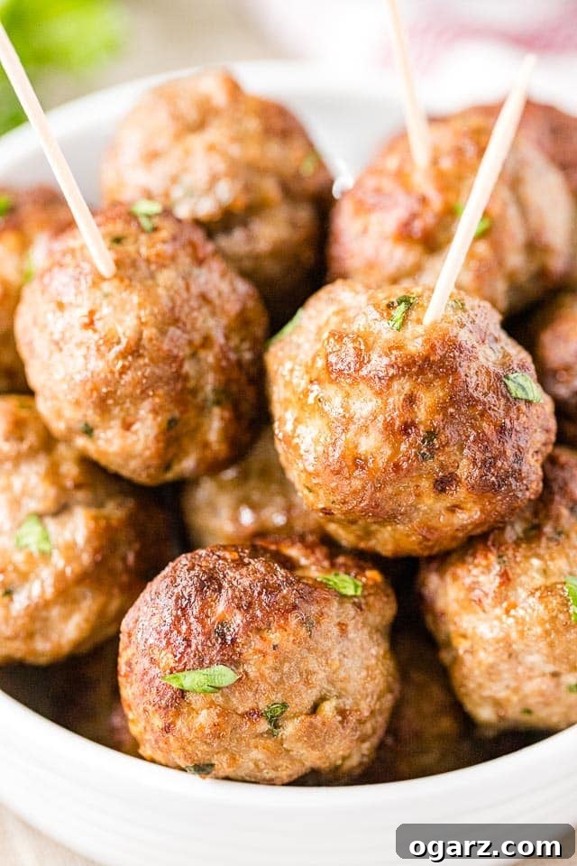 Juicy Air Fryer Meatballs in Minutes 2 A bowl of perfectly cooked, golden-brown air fryer meatballs garnished with fresh parsley, ready to be served.
