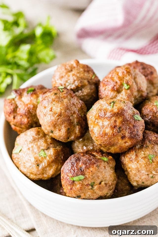 Juicy Air Fryer Meatballs in Minutes 4 Cooked air fryer meatballs in a bowl, garnished with fresh chopped parsley, ready to be served.