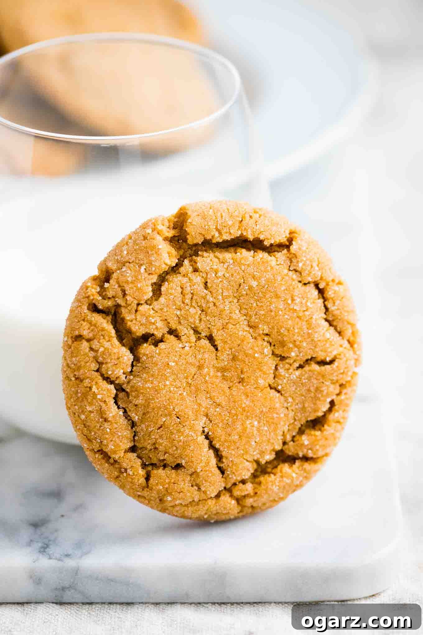 Irresistible Spiced Ginger Snaps 2 A Gingersnap Cookie with a glass of milk on a marble board, evoking a cozy holiday scene.