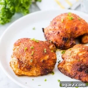 Beautifully air-fried chicken thighs on a plate, showcasing their crispy skin and juicy interior, garnished with fresh herbs.
