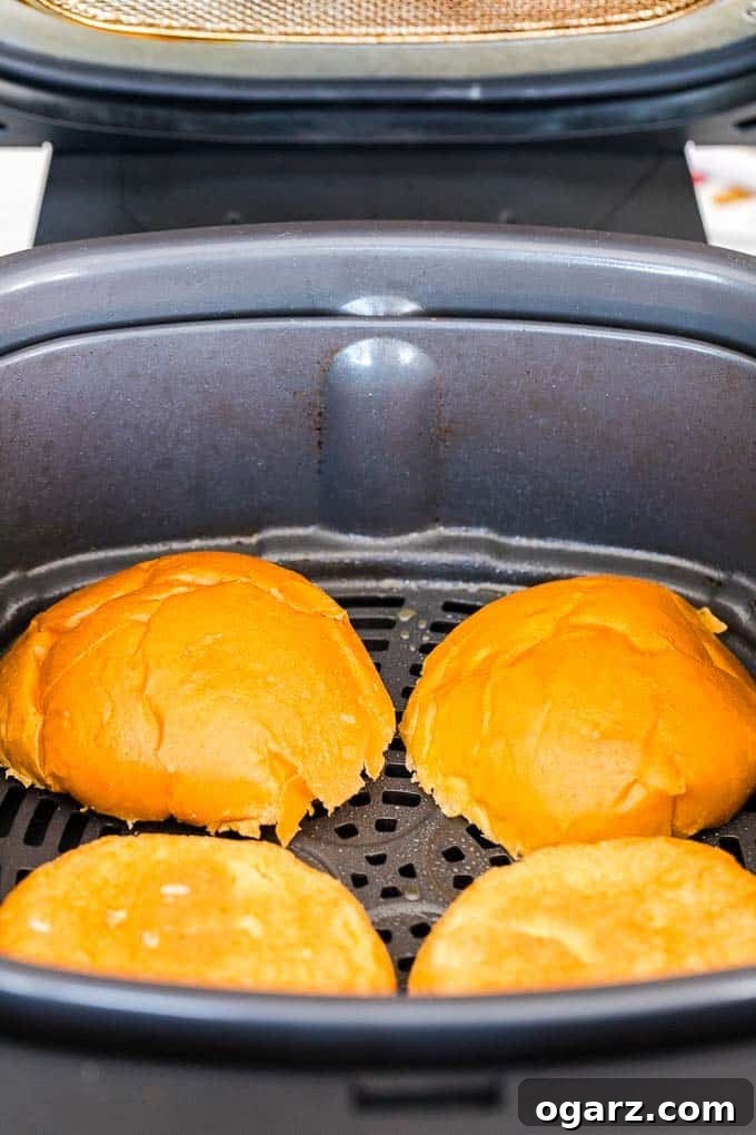 Toasted hamburger buns in the Air Fryer Basket, ready for assembly
