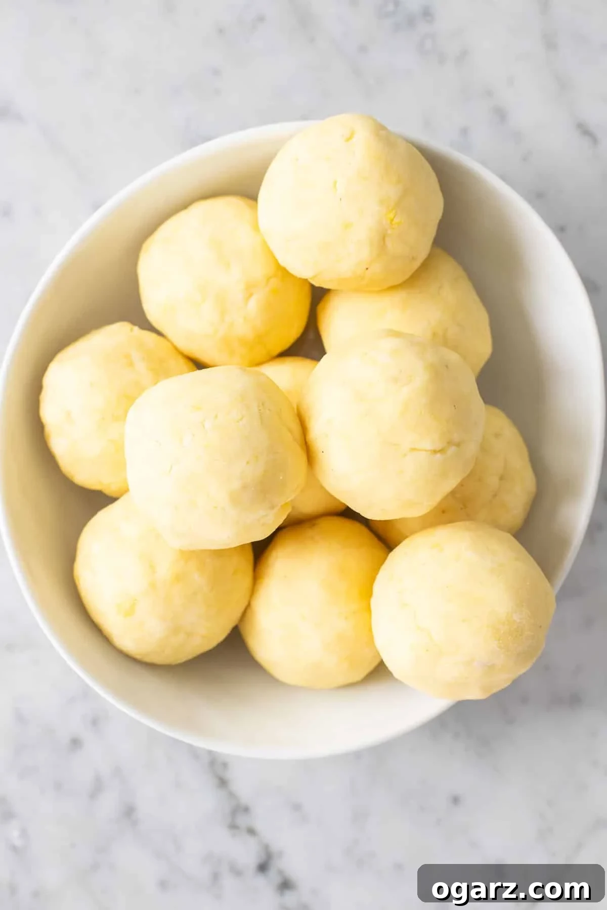 Pillowy Potato Bites 13 Ten perfectly shaped, uncooked potato dumplings (Knödel) neatly arranged, ready for their gentle cooking process.