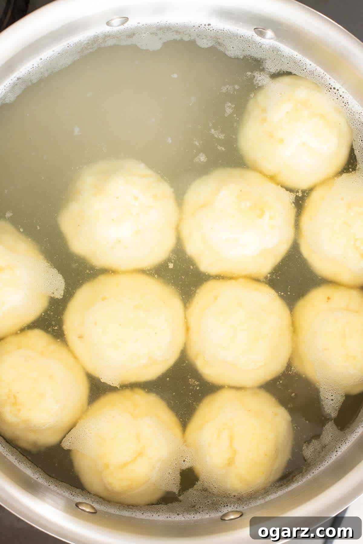 Pillowy Potato Bites 15 Cooked potato dumplings gracefully floating on the surface of the simmering water, indicating they are perfectly done.