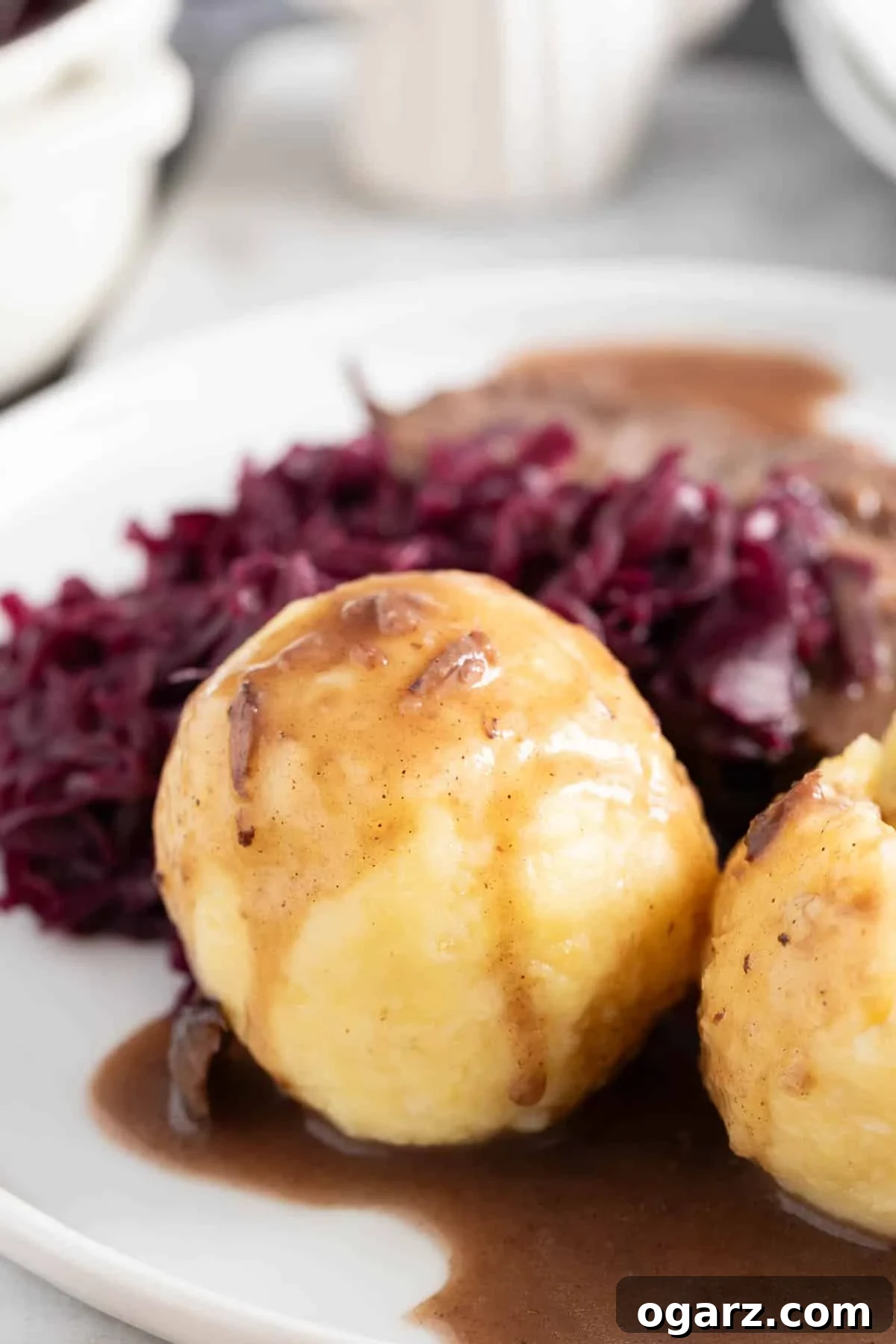 Pillowy Potato Bites 16 A complete traditional German meal: Kartoffelkloesse drenched in gravy, alongside slices of Sauerbraten and vibrant red cabbage, beautifully presented on a plate.