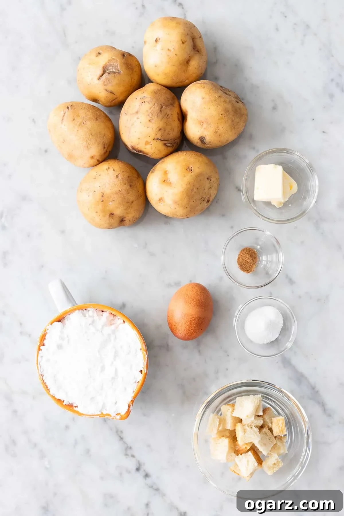 Pillowy Potato Bites 3 A carefully arranged photo of all the essential ingredients laid out for making Kartoffelkloesse, including potatoes, potato starch, and an egg.