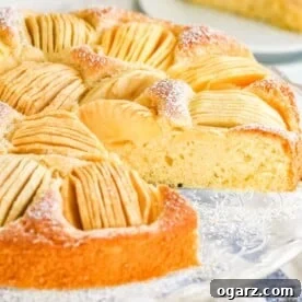 A cake with quartered apples sunken into the top on a glass serving platter.