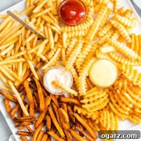 Different french fries on a platter with condiments