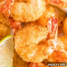 A close up of air-fried coconut shrimps next to a slice of lime.