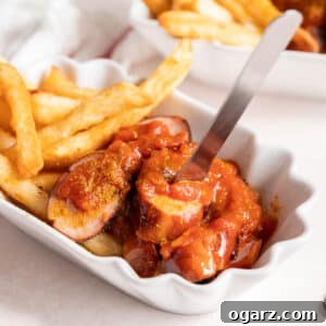 Currywurst with fries in a white serving dish.