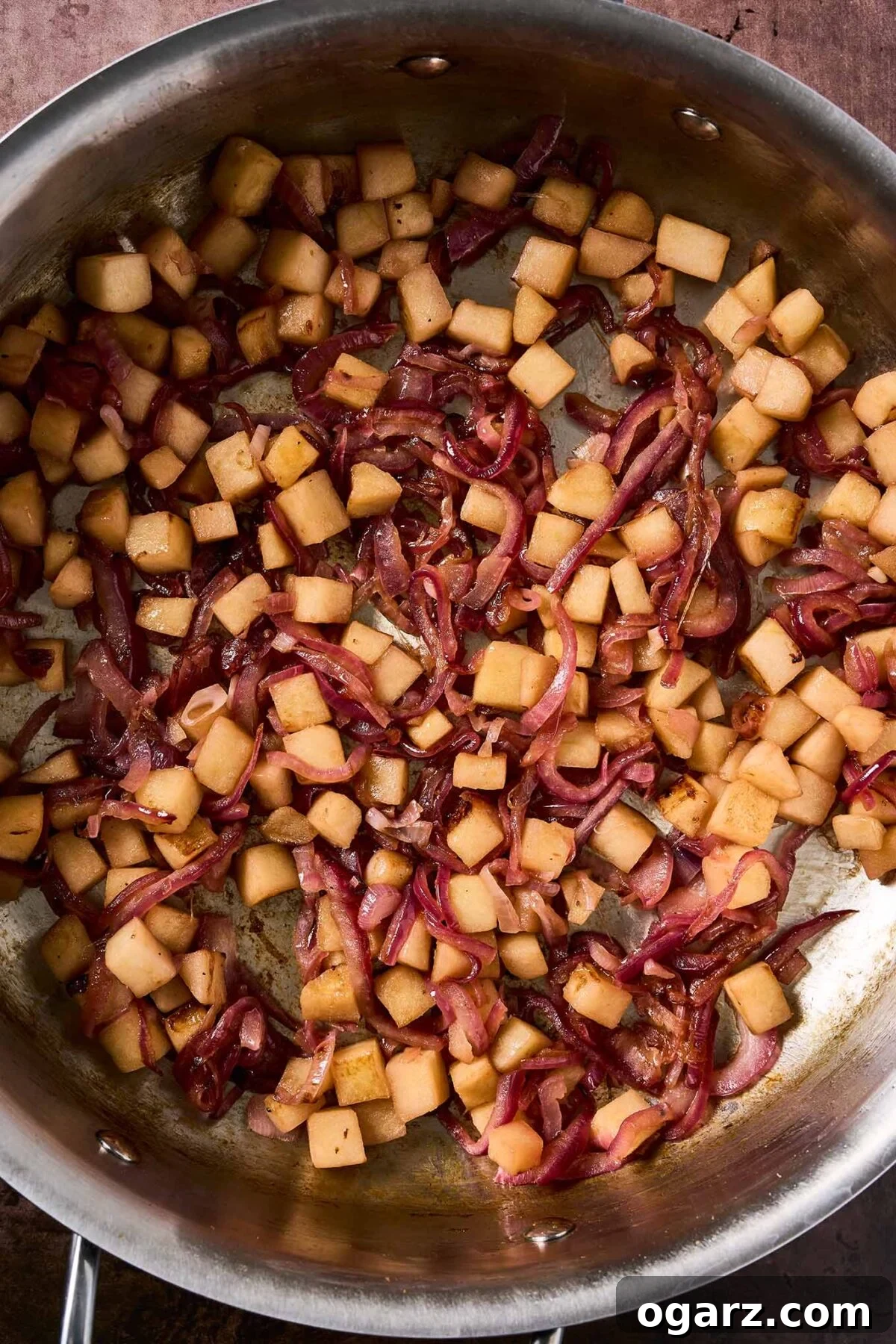 Caramelized Apples and Onions for Roasts and Salads 5 Diced apples beginning to brown alongside softened, lightly caramelized red onions in a stainless steel skillet.